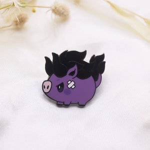May include: A purple enamel pin featuring a cartoon pig with black hair and a bandage. The pig has a grumpy expression and a pink snout. The pin is set against a white background.