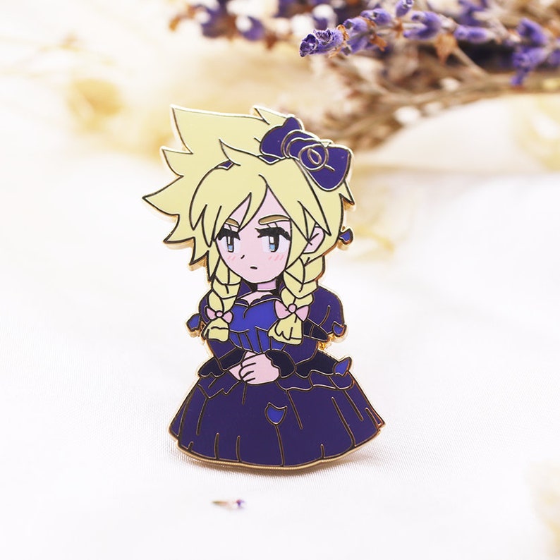 May include: A gold-coloured enamel pin featuring a cartoon character with blonde hair, wearing a purple dress with a pink bow. The character has a pink bow in their hair and is looking to the side.