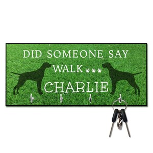 May include: Green key holder with a black silhouette of a dog and the text "Did someone say walk Charlie".