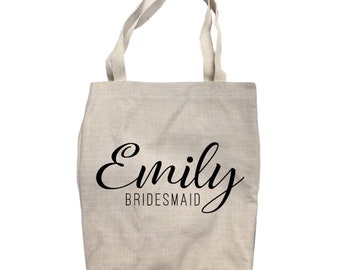 May include: A natural-colored canvas tote bag with black handles and the text "Emily Bridesmaid" printed on the front.