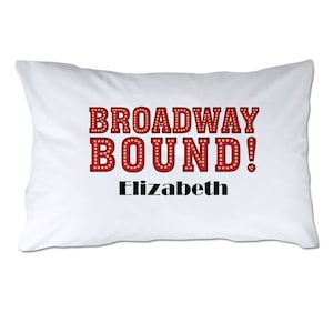 May include: White pillow with red text that says "BROADWAY BOUND!" and the name "Elizabeth" underneath.
