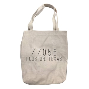 May include: A beige canvas tote bag with black text that reads "77056 HOUSTON, TEXAS".