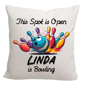May include: White pillow with a colorful bowling graphic and the text "This Spot is Open Linda is Bowling".