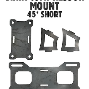 Könnte beinhalten: Ein Viair Kompressor-Halterungsset 45* short bestehend aus vier dunkelgrauen Metallteilen mit vorgestanzten Montagelöchern und Schlitzen. Der Text VIAIR COMPRESSOR MOUNT 45* SHORT und MADE IN THE USA @SPORTTRUCKPROS ist schwarz auf weißem Grund.