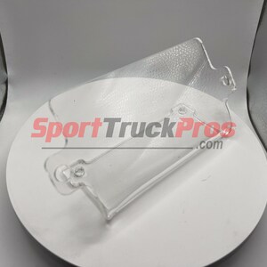 May include: Clear plastic automotive part with two holes and a SportTruckPros.com logo.