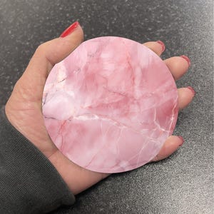 May include: A round pink and white marble coaster with a swirling pattern.
