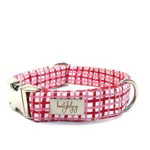 Könnte beinhalten: Rotes und pinkfarbenes kariertes Hundehalsband mit einer silbernen Schnalle und einem Anhänger mit der Aufschrift "kirstylishpup".