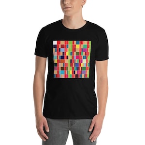 Puede incluir: Una camiseta negra con un estampado geométrico de colores en la parte delantera. El estampado está formado por cuadrados de diferentes colores, incluyendo rojo, verde, azul, amarillo y naranja.