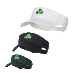 May include: Three visor hats with a green shamrock embroidered on the front. The hats are white, black, and green.