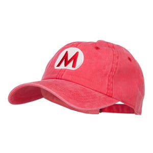 May include: A red baseball cap with a white circle and a red "M" embroidered on the front.