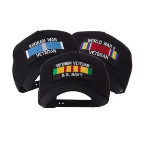May include: Three black baseball caps with embroidered patches. One reads "KOREAN WAR VETERAN" with a blue and silver ribbon. Another says "WORLD WAR II VETERAN" with a rainbow ribbon. The third says "VIETNAM VETERAN U.S. NAVY" with a yellow, red, and green ribbon.