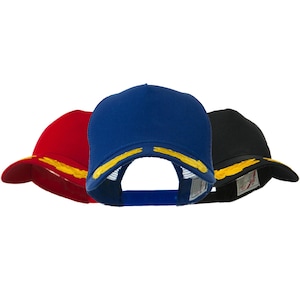 Peut inclure: Trois casquettes de camionneur avec dos en mesh. Les casquettes sont rouge, bleue et noire avec des ailes brodées en or sur le devant.