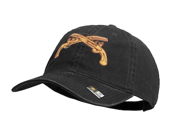 May include: Black baseball cap with a curved brim. The cap features an embroidered design of two crossed pistols in gold. The cap has a metal adjustable buckle closure on the back.