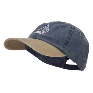 May include: A navy blue baseball cap with a tan peak. The cap has a white embroidered sailboat design on the front. An adjustable strap is visible at the back. This hat is a casual accessory.