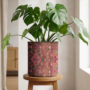 Peut inclure: Un grand Monstera en pot avec des feuilles vertes vibrantes. La plante est dans un pot cylindrique avec un motif marron. Le pot repose sur un petit tabouret rond en bois, créant un affichage naturel et décoratif.