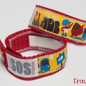 May include: Two red and yellow fabric wristbands with embroidered designs. One band features a tent, logs, and a person with a wheelbarrow. The other band has a truck and an SOS label. The text "SOS inside" is visible.