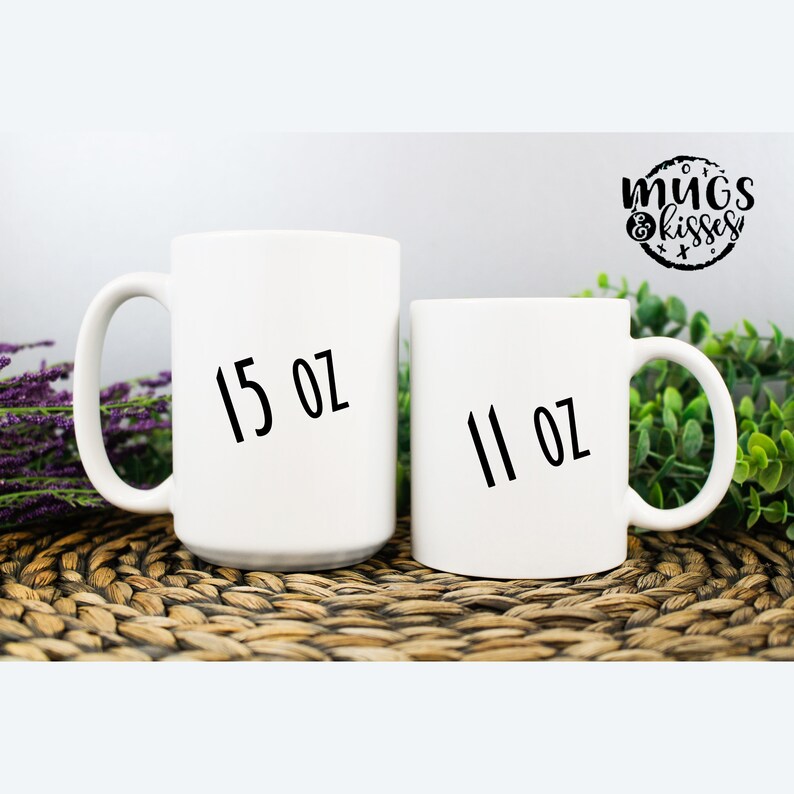 May include: Two white ceramic mugs with black text. The larger mug is 15 oz and the smaller mug is 11 oz.