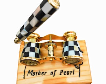 May include: A decorative pair of opera glasses with a gold-tone frame and black and white checkered accents. The handle and eyepieces feature a mother-of-pearl design. The wooden base is engraved with the words "Mother of Pearl."