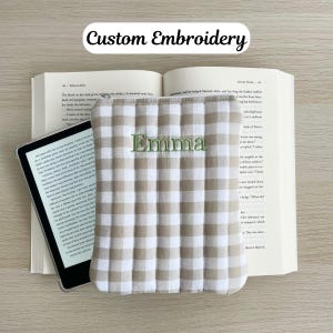 May include: A beige and white checkered book cover with the name "Emma" embroidered in green thread.