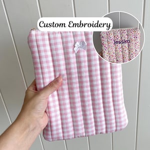 Könnte beinhalten: Rosa-weiß karierte, gesteppte Clutch mit weißer Schleife und goldenem Reißverschluss. Der Text "Custom Embroidery" steht darüber. Ein kleineres Bild zeigt eine Clutch mit Blumenmuster und dem Namen "Jessica".