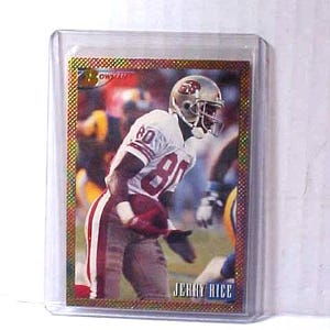 May include: A football trading card featuring Jerry Rice in a white and red uniform with the number 80. The card is in a protective plastic sleeve. The card has a gold border and the name "JERRY RICE" is printed at the bottom.