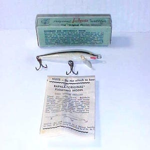 May include: A silver and white Rapala Original Floating Model fishing lure with red accents. The lure is on a white background with a box and instructions. The instructions say "Do not attach to hook" and "Rapala Original Floating Model".