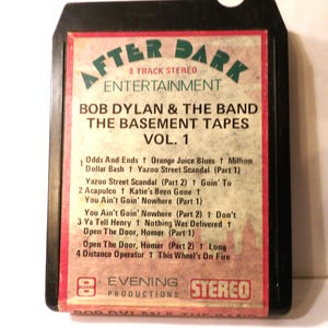 May include: An 8-track stereo tape of Bob Dylan & The Band's "The Basement Tapes Vol. 1." The label features the text "After Dark Entertainment" in green and red. The track list is visible.