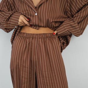 May include: A brown and white striped pyjama set with a button-up shirt and wide-leg trousers.