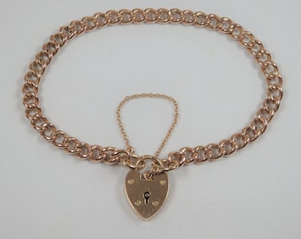 May include: A gold chain bracelet with a heart-shaped padlock charm. The chain is a curb style and the padlock has a keyhole.