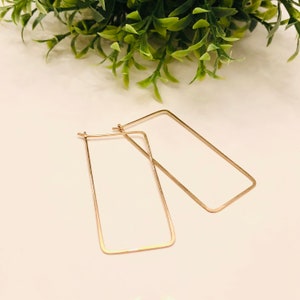 May include: A pair of gold rectangle hoop earrings. The earrings are simple and elegant.