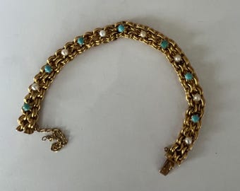 May include: Gold-toned bracelet with a double chain design. The bracelet is adorned with small, round, turquoise and pearl-like beads. The clasp is open, and a small chain hangs from the end. The bracelet is on a white surface.