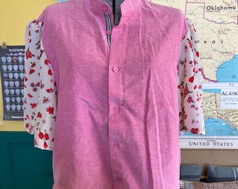 May include: A pink button-down shirt with a mandarin collar and sheer sleeves. The sleeves are white with a floral pattern in red and pink. The shirt is displayed on a mannequin.