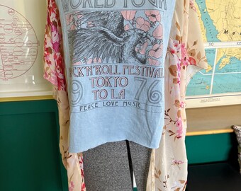 May include: A light blue t-shirt with a graphic that reads "WORLD TOUR ROCK'N'ROLL FESTIVAL TOKYO TO LA 76 PEACE LOVE MUSIC." The shirt is paired with a sheer floral kimono in shades of pink and cream.