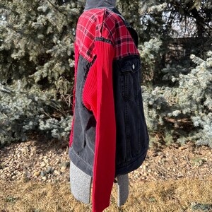 Puede incluir: Chaqueta vaquera con canes&uacute; a cuadros rojos y negros y mangas de punto acanalado rojo. La chaqueta tiene cuello negro y cierre de botones. La chaqueta se exhibe en un maniqu&iacute; al aire libre.