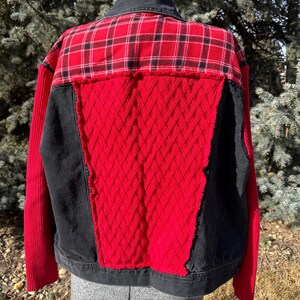 Puede incluir: Chaqueta patchwork con cuello y base de mezclilla negra. La espalda presenta un estampado de cuadros rojos y negros en la parte superior, con un patr&oacute;n de diamantes rojos texturizado en el centro. Paneles negros flanquean el patr&oacute;n de diamantes rojos y las mangas son rojas.
