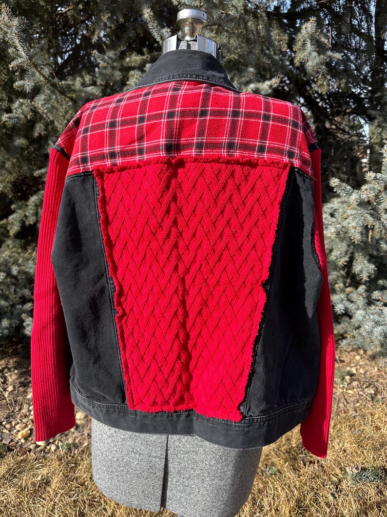 Puede incluir: Chaqueta patchwork con cuello y base de mezclilla negra. La espalda presenta un estampado de cuadros rojos y negros en la parte superior, con un patr&oacute;n de diamantes rojos texturizado en el centro. Paneles negros flanquean el patr&oacute;n de diamantes rojos y las mangas son rojas.