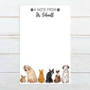 May include: A white notepad with the text "A Note From Dr. Schmitt" at the top. The bottom of the notepad features a line of watercolor illustrations of a rabbit, a golden retriever, two cats, a Boston terrier, a cat, and a Dalmatian.