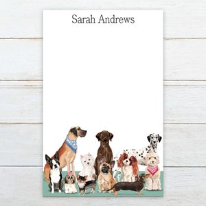 May include: A white notepad with the name "Sarah Andrews" printed at the top. The bottom of the notepad features a group of dogs of various breeds, including a Dalmatian, a Great Dane, a Labrador Retriever, a French Bulldog, a Chihuahua, a Boston Terrier, a Cavalier King Charles Spaniel, a Shih Tzu, and a Dachshund.