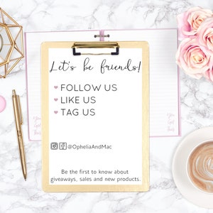 May include: A flat lay featuring a gold clipboard with the text "Let's be friends!" and social media prompts. Accompanying items include a gold pen, candle holder, pink candles, and a cup of coffee with latte art, all on a marble surface.