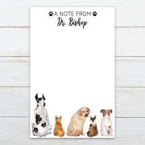 May include: White notepad with the text "A Note From Dr. Bishop" and paw prints. The bottom of the notepad features watercolor illustrations of a Great Dane, a golden retriever, a Jack Russell Terrier, and two cats.