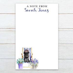 May include: White notepad with the text "A Note From Sarah Jones" in blue. A watercolor illustration of a black dog wearing sunglasses sitting in a blue and white striped beach chair is at the bottom.