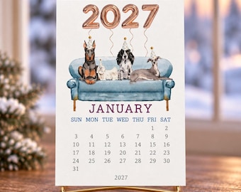 May include: A 2027 January calendar page featuring a watercolor illustration of four dogs wearing party hats sitting on a blue sofa. Above the dogs are rose gold balloon numbers reading 2027. The calendar grid displays the days of the month.