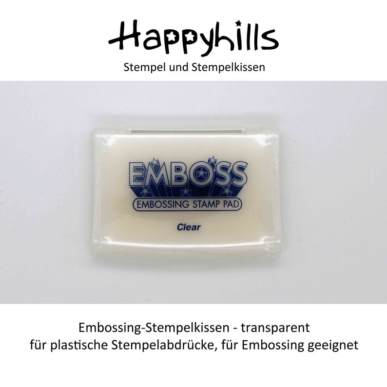 May include: A white embossing stamp pad with the text "EMBOSS" and "EMBOSSING STAMP PAD" in blue lettering. The pad is labeled "Clear".