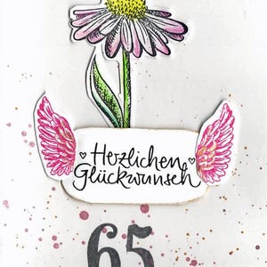 Op de afbeelding: Een witte kaart met roze en gouden glitteraccenten. Een roze bloem met een gele kern bevindt zich bovenaan de kaart. Onder de bloem bevinden zich twee roze vleugels met gouden glitteraccenten. De tekst "Herzlichen Gl&uuml;ckwunsch" staat op de kaart. Het nummer 65 staat onderaan de kaart in het zwart.