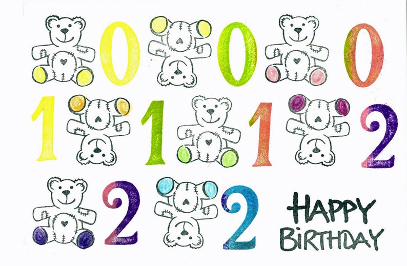 Op de afbeelding: Een kleurrijke kaart met de getallen 0, 1 en 2 die meerdere keren worden herhaald. Elk getal wordt omringd door een teddybeerillustratie. De kaart zegt "Happy Birthday" met een zwarte stift.