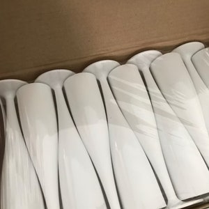 May include: A box of white plastic champagne flutes. The flutes are arranged in rows and are wrapped in plastic.