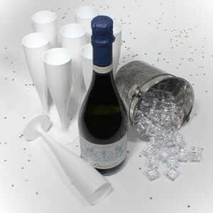 May include: A bottle of Prosecco champagne in a silver ice bucket with ice cubes and white plastic champagne flutes.