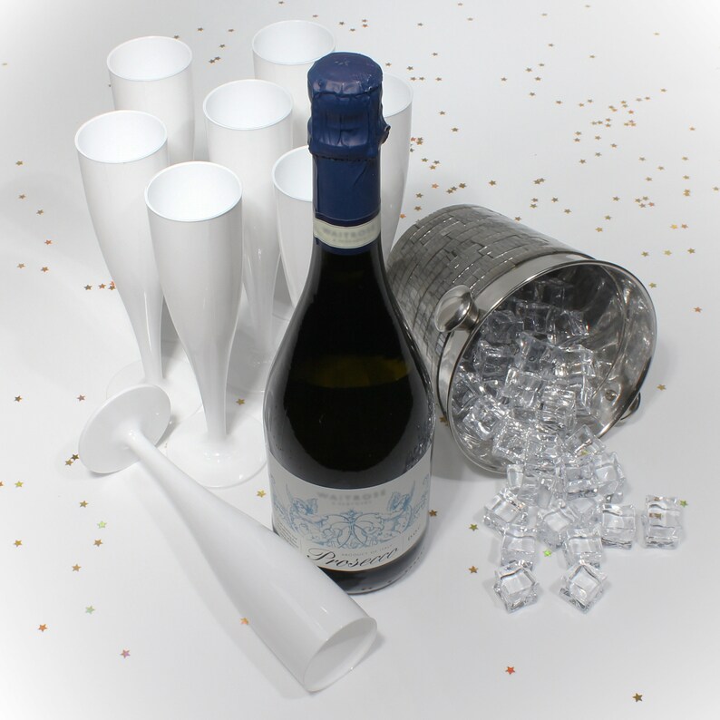 May include: A bottle of Prosecco champagne in a silver ice bucket with ice cubes and white plastic champagne flutes.
