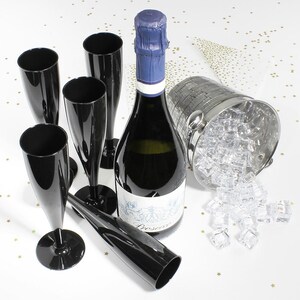 May include: A set of five glossy black plastic champagne flutes arranged around a bottle of Prosecco with a blue foil-wrapped cork. A silver metallic ice bucket filled with clear acrylic ice cubes sits to the right of the bottle.
