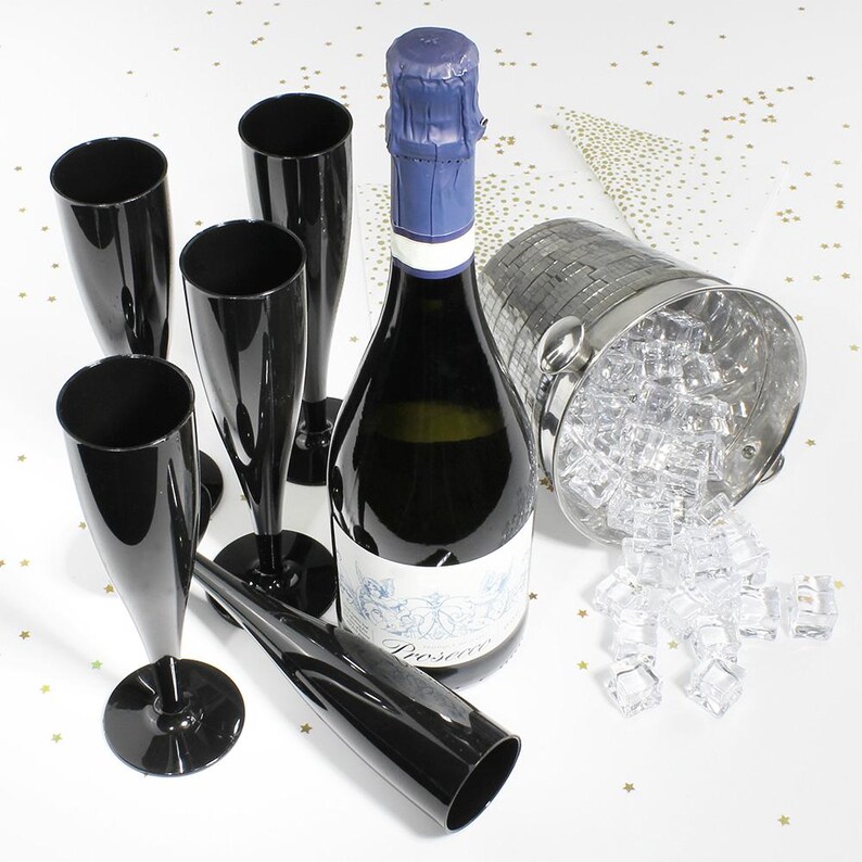 May include: A set of five glossy black plastic champagne flutes arranged around a bottle of Prosecco with a blue foil-wrapped cork. A silver metallic ice bucket filled with clear acrylic ice cubes sits to the right of the bottle.